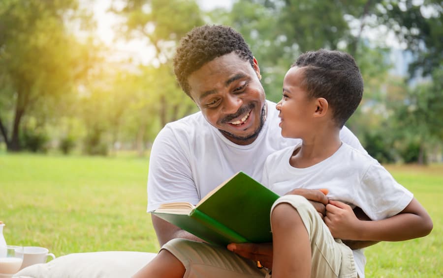 Father reading to his son outdoors.